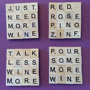 May include: A set of wooden letter tiles spelling out the phrases "Just need more wine", "Red rose pinot zinfandel", "Talk less wine more", and "Pour some more wine".