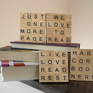 May include: A stack of books with wooden letter tiles spelling out the phrases "Just One More Page", "We Love To Read", "Live Love Read Rest", and "Hard Core Book Nerd".