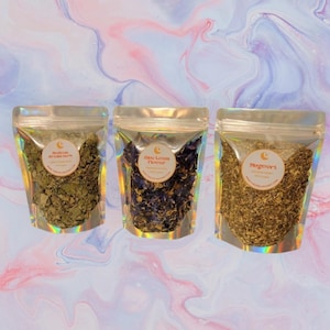 May include: Three clear, resealable pouches filled with dried herbs and flowers. The pouches are labeled with the names "Mexican Dream Herb", "Blue Lotus Flower", and "Mugwort". The background is a soft blend of pink, blue, and white.