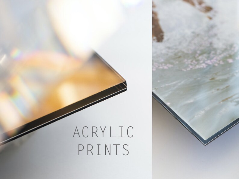 May include: Close-up of the edge of two acrylic prints. The print on the left has a rainbow-like sheen. The print on the right has a light blue and white abstract design. The text "ACRYLIC PRINTS" is printed below the images.