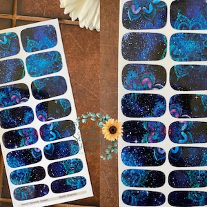 May include: A sheet of 12 nail decals featuring a galaxy background and blue mandala designs. The decals are labelled "Sweet Serenity Haven" and "Star Charms".