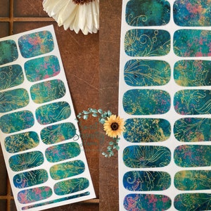 Peut inclure: Une feuille de décalcomanies pour ongles de couleur sarcelle et or avec un motif floral. Les décalcomanies sont conçues pour être appliquées sur les ongles.