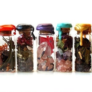 Op de afbeelding: Tien kleine glazen flesjes met kurkstoppen en kleurrijke waszegels. Elk flesje is gevuld met verschillende gedroogde kruiden, bloemen en kristallen.
