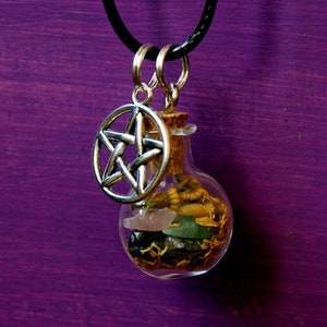 Może przedstawiać: Srebrny wisiorek w kształcie pentagramu zawieszony na czarnym sznurkowym naszyjniku z małą szklaną butelką wypełnioną kryształami i ziołami.