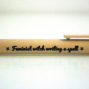May include: A wooden pen with the text "Feminist witch writing a spell" engraved on it.
