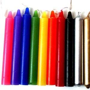 Könnte beinhalten: Ein Set mit zehn kleinen Kerzen in verschiedenen Farben, darunter rosa, lila, blau, grün, gelb, orange, rot, schwarz, silber und gold. Die Kerzen sind alle etwa 7,5 cm lang und haben eine spitze Spitze.
