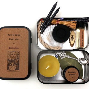 Puede incluir: Un kit de altar de viaje en una caja de metal. El kit incluye velas, incienso, una concha, una pequeña escoba, una botella de aceite, una runa de madera, una vela, una cuchara, una hoja y un tarro de eucalipto globulus. La caja tiene el texto "Autel de borage, Trabel altar, Purification."
