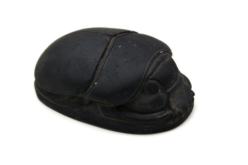 Puede incluir: Un escarabajo negro de piedra pulida. El escarabajo est&aacute; tallado con detalle y tiene un acabado liso y brillante.