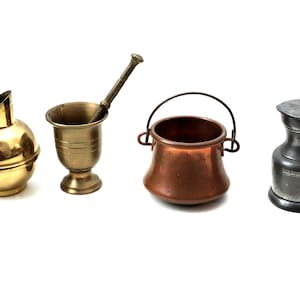 May include: A set of four miniature antique-style kitchenware items. A brass pitcher, a brass mortar and pestle, a copper pot with a wire handle, and a pewter pitcher with a lid.