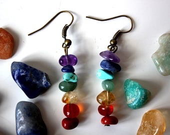 May include: A pair of dangle earrings with a rainbow of gemstones. The earrings are made with amethyst, lapis lazuli, turquoise, green aventurine, citrine, carnelian, and red jasper.