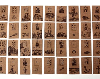 May include: A set of 36 brown playing cards with black ink illustrations. The cards are numbered 1 through 36 and feature various images, including a ship, a church, a tree, a bear, a star, a bird, a castle, a cliff, a bottle, a heart, a ring, a fish, an envelope, a key, an anchor, and a cross.