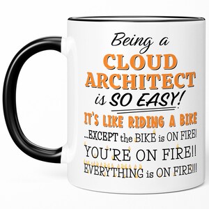 May include: White ceramic coffee mug with a black handle and black rim. The mug has a humorous quote about being a cloud architect, "Being a Cloud Architect is so easy! It's like riding a bike...EXCEPT the BIKE is ON FIRE! YOU'RE ON FIRE!! EVERYTHING is ON FIRE!!!"