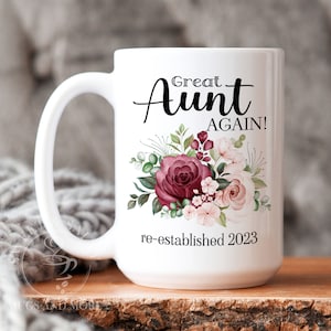 May include: White ceramic mug with a floral design in shades of pink and burgundy. The text "Great Aunt Again! re-established 2023" is printed on the mug.
