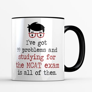 May include: White ceramic mug with a black handle and rim. The mug features the text "I've got 99 problems and studying for the MCAT exam is all of them." A cartoon illustration of a person wearing glasses is above the text.