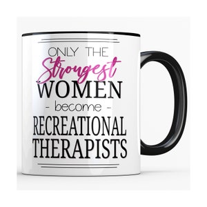 May include: White ceramic mug with a black handle and rim. The mug features the text "ONLY THE Strongest WOMEN - become - RECREATIONAL THERAPISTS" in black and pink lettering.