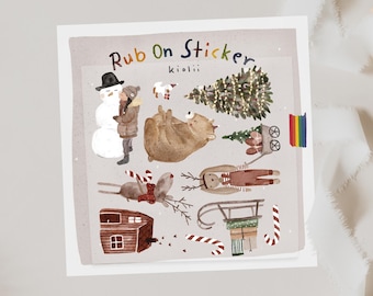 May include: A sheet of Rub On Stickers by kiolii featuring watercolor illustrations of a snowman, a person in a winter coat, a bear, a Christmas tree, a dog, a reindeer, a wooden house, a sled with gifts, and candy canes.