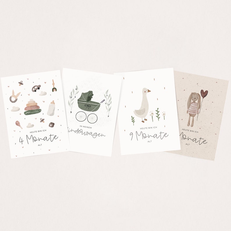 May include: Four illustrated cards with a baby theme. The first card shows a baby in a stroller with the text "In meinem Kinderwagen". The second card shows a baby with the text "Heute bin ich 4 Monate alt". The third card shows a goose with the text "Heute bin ich 9 Monate alt". The fourth card shows a bunny with a balloon with the text "Heute bin ich 9 Monate alt".