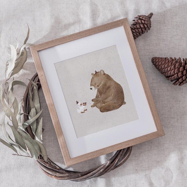 May include: A framed illustration of a brown bear and a white cat sitting together on a beige background. The bear is looking at the cat, and the cat is looking at the bear.