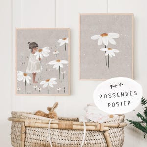 May include: Two framed prints with a gray background and white daisies. The print on the left shows a girl in a white dress holding a daisy. The print on the right shows a single daisy with three stems.