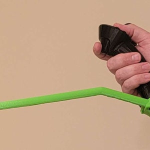 May include: A black and green 3D printed VR controller with a long green handle.