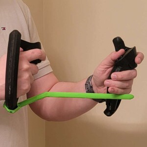 May include: A person is holding two black 3D printed hand grips connected by a bright green bar.