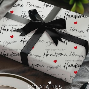 May include: A white gift box with a black ribbon and a repeating pattern of red hearts and the text "Happy Valentines Day" and "Handsome I love you!"