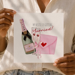 Peut inclure: Une carte de vœux carrée avec une illustration à l'aquarelle d'une bouteille de champagne, deux flûtes avec des cerises et une enveloppe rose avec un cœur rouge. Le texte indique : My bestie is getting Married ! Le fond est blanc.