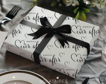 Puede incluir: Una caja de regalo blanca con una cinta negra y un patrón de corazones y el texto "Happily ever after".