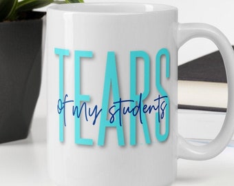 May include: White ceramic coffee mug with the text "Tears of my students" in blue and teal lettering.