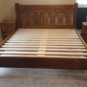 Puede incluir: Un marco de cama de madera marr&oacute;n oscuro con una cabecera de listones y una base de listones. El marco de cama est&aacute; en un dormitorio con una mesita de noche y una c&oacute;moda.