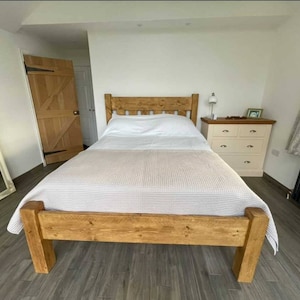Puede incluir: Un marco de cama de madera con un acabado marr&oacute;n claro. La cama tiene un dise&ntilde;o sencillo con una cabecera y un piecero. La cama est&aacute; hecha de madera maciza y tiene una veta de madera natural.
