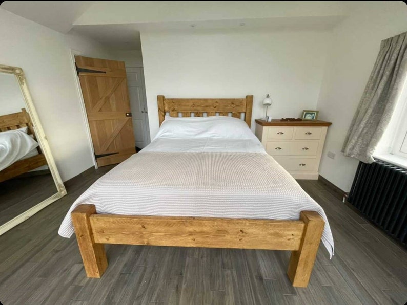 Puede incluir: Un marco de cama de madera con un acabado marr&oacute;n claro. La cama tiene un dise&ntilde;o sencillo con una cabecera y un piecero. La cama est&aacute; hecha de madera maciza y tiene una veta de madera natural.