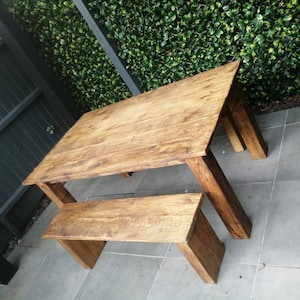 May include: A rustic wooden table and bench set, both made of natural wood with a warm brown finish. The table has a rectangular top and is supported by four sturdy legs. The bench is shorter and has a similar design.