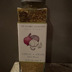 May include: A clear glass spice jar with a silver lid, labeled "The Gourmet Collection" and "Garlic & Onion Spice Blend." The label features illustrations of garlic and onion. Net weight is 8.46 ounces (240g).