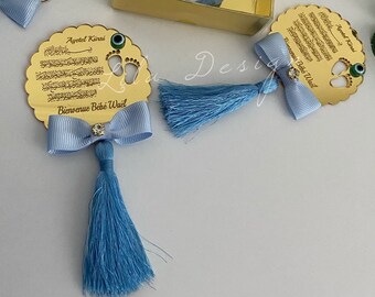 May include: Gold circular plaque with a blue tassel and bow. The plaque features Arabic text, a blue evil eye charm, and the words "Ayet el Kursi" and "Bienvenue Bébé Waël".