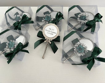 May include: Small silver-toned hand mirrors with a decorative floral arrangement and dark green ribbon. Each mirror is packaged in a clear plastic box. One mirror has a tag that reads "Mis XV Daniela Espinoza 5.20.2023".