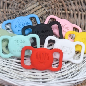 May include: A collection of colorful silicone dog collar buckles with engraved names and phone numbers. The buckles are in various colors, including red, blue, green, yellow, black, and white.