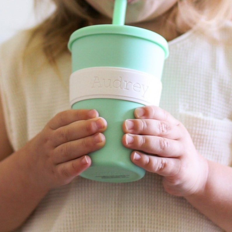 Peut inclure: Un gobelet en silicone vert menthe avec un couvercle et une paille assortis, dot&eacute; d'une bande en silicone blanc autour du centre. La bande blanche est emboss&eacute;e avec le pr&eacute;nom Audrey dans une police simple et claire pour une meilleure prise.