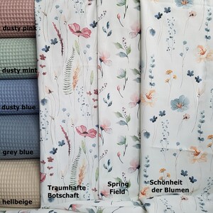 May include: A close-up of four fabric swatches with different colors and textures. The swatches are labeled "dusty pink", "dusty mint", "dusty blue", "grey blue", and "hellbeige". The fabric swatches are next to three fabric samples with watercolor floral patterns. The floral patterns are labeled "Traumhafte Botschaft", "Spring Field", and "Sch&ouml;nheit der Blumen".