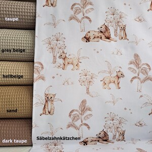 May include: White fabric with a repeating pattern of brown palm trees and brown lynx. The text "S&auml;belzahnk&auml;tzchen" is printed in brown at the bottom of the fabric.