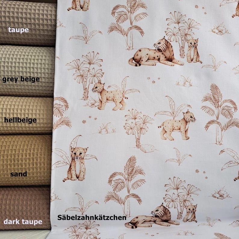 May include: White fabric with a repeating pattern of brown palm trees and brown lynx. The text "S&auml;belzahnk&auml;tzchen" is printed in brown at the bottom of the fabric.