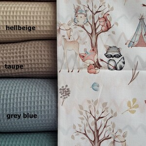 May include: Five fabric swatches in different colors: dusty pink,  hellbeige, taupe, grey blue, and adriatic blue. The swatches are arranged vertically, with the dusty pink swatch at the top and the adriatic blue swatch at the bottom.  A white fabric with a woodland animal print is shown to the right of the swatches. The print features a tree with a fox, a raccoon, a deer, and a squirrel. The text "Waldfreunde Boho" is printed on the fabric.