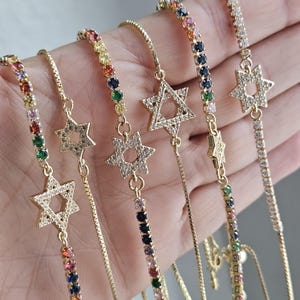 May include: Five gold chain bracelets with a star of David charm. Each bracelet features a different colored chain with various gemstones.