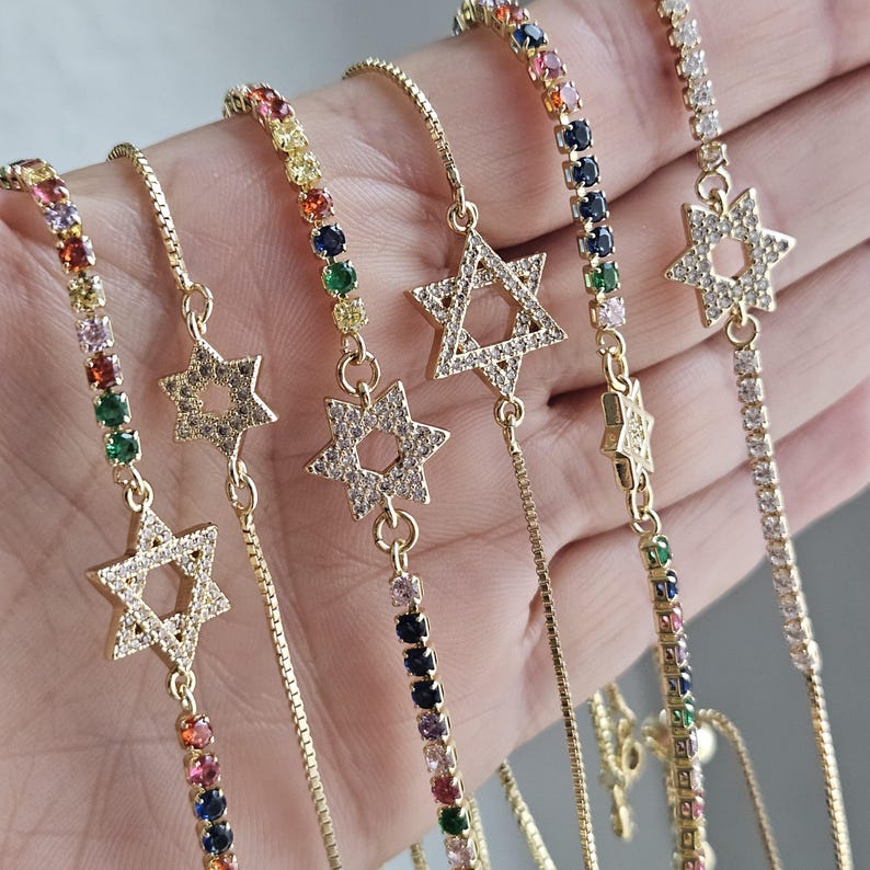 May include: Five gold chain bracelets with a star of David charm. Each bracelet features a different colored chain with various gemstones.