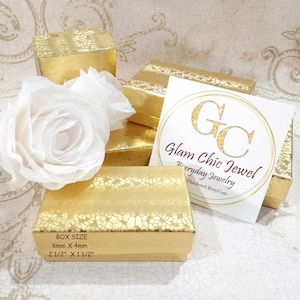 May include: Gold jewelry boxes with a textured pattern. The boxes are stacked on top of each other. The top box has a white label with the text "Glam Chic Jewel Everyday Jewelry GlamChicJewelEtsy.com". The box size is 6mm x 4mm or 2 1/2" x 1 1/2".