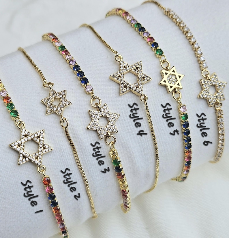 May include: Six gold bracelets with a star of David charm. Each bracelet has a different colored chain with rainbow colored stones. The bracelets are labeled with the text "Style 1", "Style 2", "Style 3", "Style 4", "Style 5", and "Style 6".