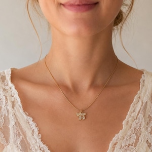 May include: A gold-toned necklace featuring a small pendant shaped like the Hebrew letter Chai, which is encrusted with small, clear, sparkling stones. The pendant hangs from a delicate, thin gold-toned chain that rests against the collarbone area.