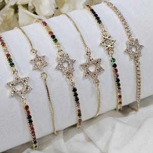 May include: Five gold chain bracelets with a star of David charm. Each bracelet features a different colored chain with small gemstones.