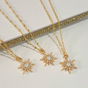May include: Three gold necklaces with starburst pendants featuring clear crystals. The starbursts are different sizes and have a delicate, feminine look.