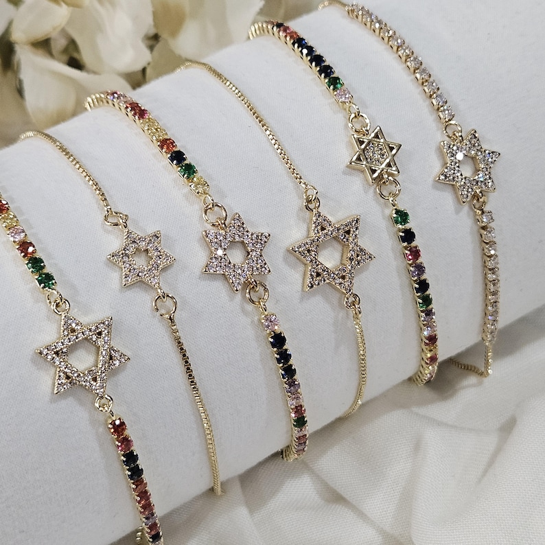 May include: Five gold chain bracelets with colorful gemstones and a star of David charm. Each bracelet has a different color combination of gemstones.